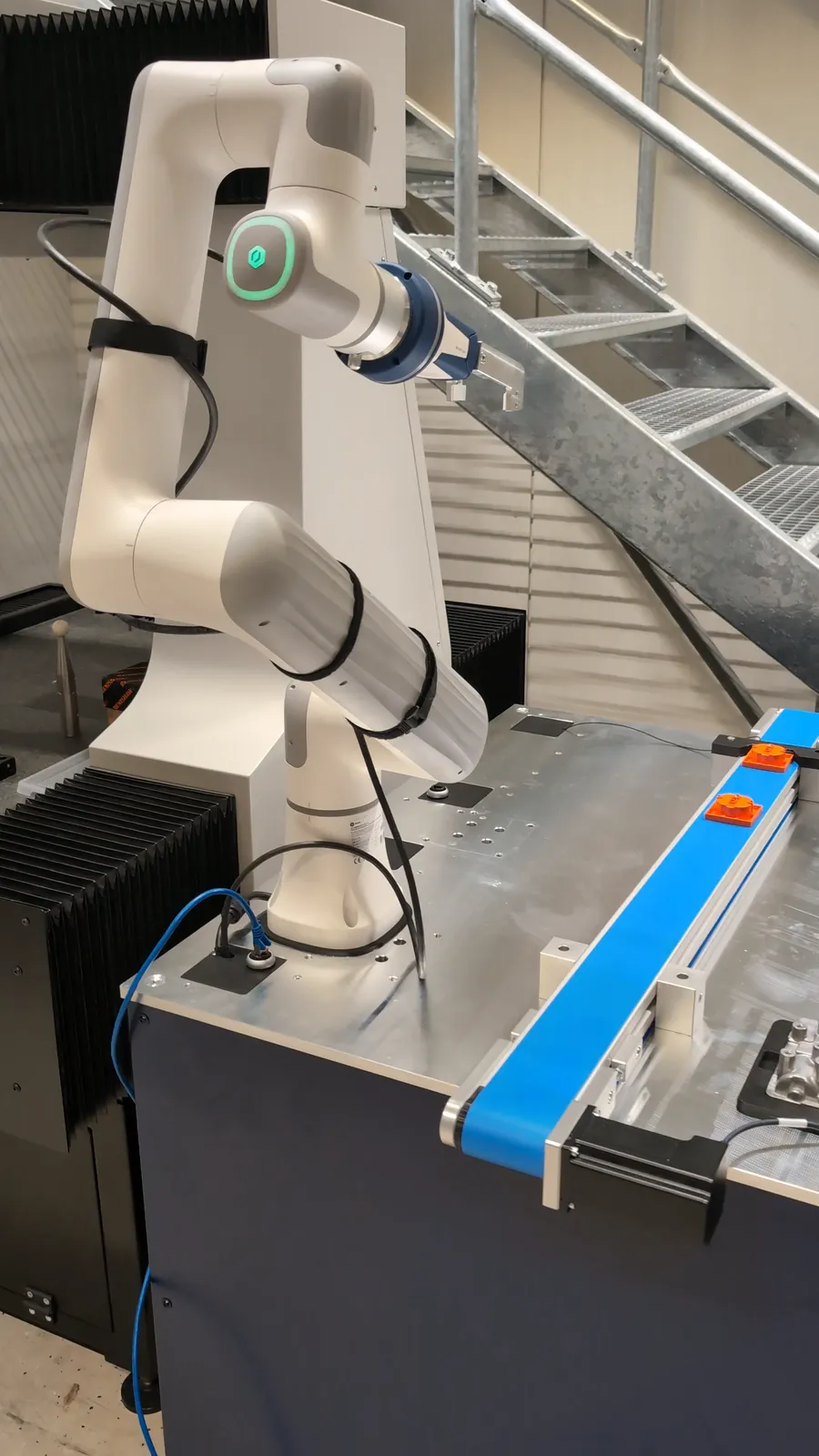Cobot be- und entlädt eine Messmaschine über ein Förderband